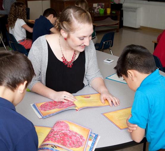 teacher reading to two children in elementary classroom