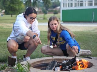 两个学生在校园里的火坑里烤棉花糖